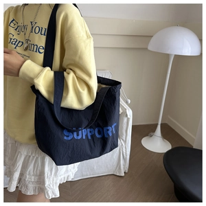 Detail of black canvas tote bag with blue Support print and white adjustable drawstring
