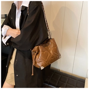 Detail of heart-shaped quilted texture and metal corner protectors on a brown shoulder bag