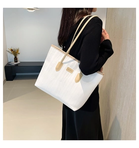 Close-up of white textured tote bag with JINGPIN metal plate worn by a model