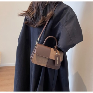 Detail view of a color-block crossbody bag featuring brown leather and suede textures
