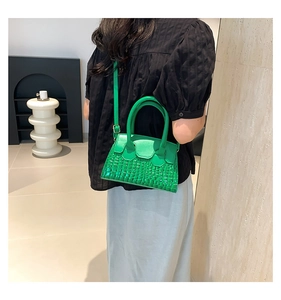 Borsa a mano verde in finta pelle di coccodrillo indossata da una modella in interno