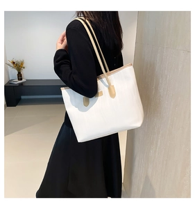 Shoulder view of white tote bag with vertical texture and tan leather straps for commuting