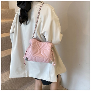 Detailed view of pink heart-quilted shoulder bag with silver chain strap and corner accents