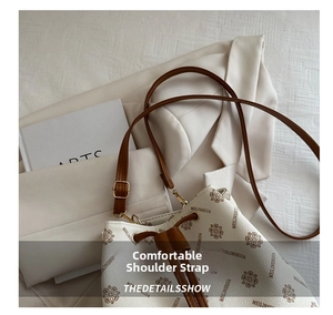 Close-up of beige bucket bag with floral monogram print and brown leather shoulder strap