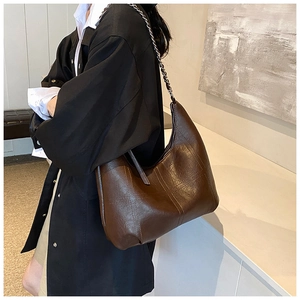 Détail d'un sac hobo marron foncé avec motifs quadrillés et bandoulière en chaîne métallique