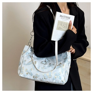 Detailed embroidery of light blue and gold butterflies on a white canvas shoulder bag