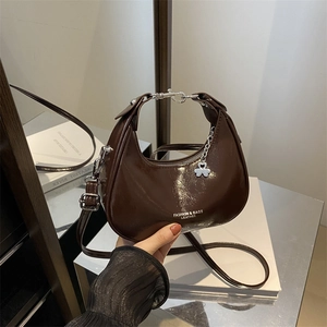 Deep brown glossy crescent shoulder bag with silver hardware and clover pendant