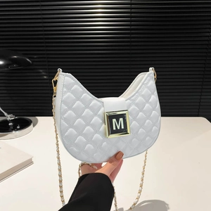 Quilted white crescent crossbody bag with gold chain strap and metallic buckle