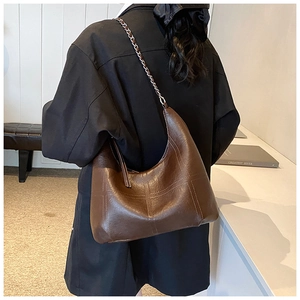Détail du sac hobo en cuir marron foncé avec coutures matelassées et chaîne en métal