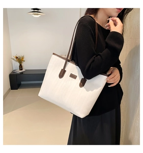 Detail of a large white tote bag with brown leather straps shown on a female model
