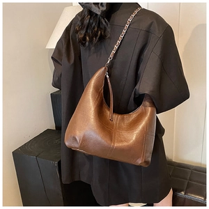 Détail du sac hobo marron foncé avec coutures matelassées et chaîne argentée à l'épaule