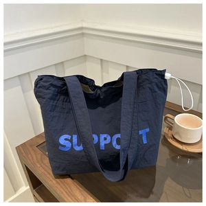 Detail of navy blue tote bag with SUPPORT print and white side drawstring adjustment
