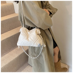 Detail of white heart-quilted shoulder bag with metal corners and chain strap