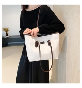 Modern white fabric tote bag with dark brown trim and top handle shown on a model