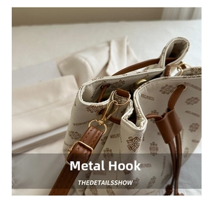 Close-up of golden metal hooks and adjustable strap details on a vintage bucket bag