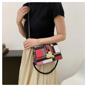 Detail of color-block crossbody bag with gold hardware worn by a model in lifestyle setting