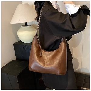 Détail du sac hobo matelassé marron foncé avec chaîne en métal et gland décoratif en cuir