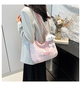 Detailed texture of pink embossed canvas bag with colorful embroidery and plush charm