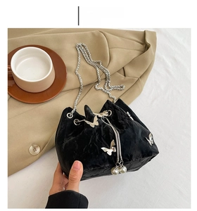 Detail of black velvet bucket bag with silver butterfly studs and pearl drawstring