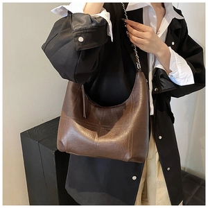 Détail du sac sous le bras en cuir marron avec coutures en croix et bandoulière chaîne