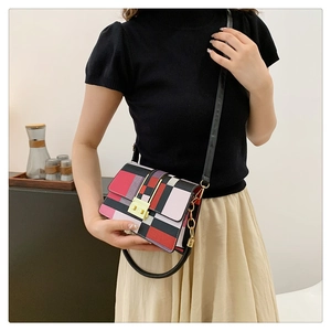 Detailed view of colorful geometric patchwork handbag worn with a chic black outfit