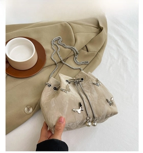 Detail of light khaki bucket bag featuring silver butterfly studs and pearl drawstring