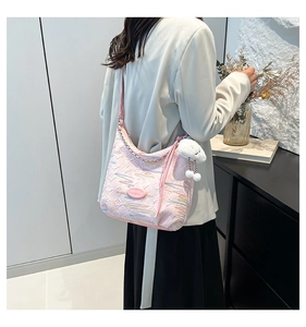 Detail of pink embroidered canvas bucket bag with plush charm and stylish strap