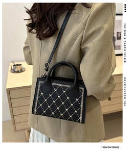 Detail of black crossbody bag featuring beige heart embroidery and classic quilted pattern