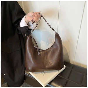 Détail du sac hobo marron foncé avec coutures en croix et texture de bandoulière chaîne