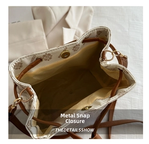 Close-up of retro monogram bucket bag with gold magnetic buckle and drawstring closure