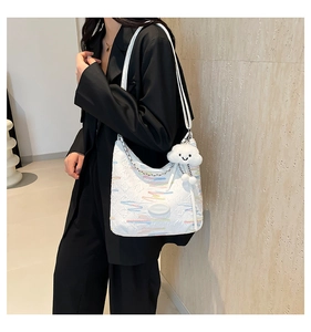Detail of white quilted canvas bag with colorful stripes and cute cloud charm accessory
