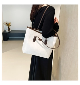 Tote bag with contrasting brown straps shown on a model for shoulder carry detail