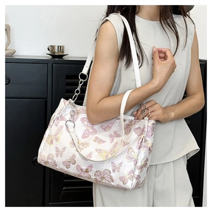 Detail of white satin shoulder bag featuring purple and gold butterfly embroidery with chain