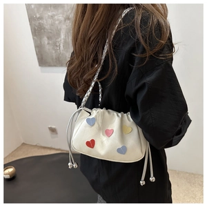 Détail d'un sac en toile blanche avec patchs cœur colorés et bandoulière chaîne argent