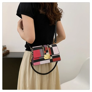 Detail of colorful geometric leather shoulder bag with gold clasp worn by a model