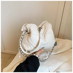 Detail of white chain shoulder bag with heart quilted pattern and metal strap