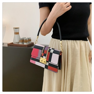 Detail of a color-block crossbody bag with gold metal clasp shown in a lifestyle setting