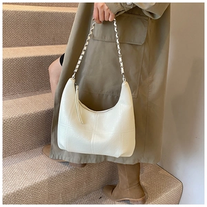 Vue détaillée du sac beige avec bandoulière chaîne argentée et motif de surpiqûres
