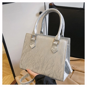 Detail of silver pleated textured handbag with double handles and gold metal hardware