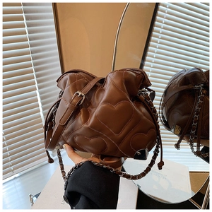 Detail shot of a brown quilted tote with heart-shaped texture and chain shoulder strap