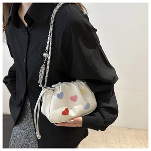 Detail of white cloud-shaped shoulder bag featuring colorful heart patches and silver chain