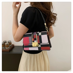 Detail of color-block geometric shoulder bag with stylish gold clasp and slim strap