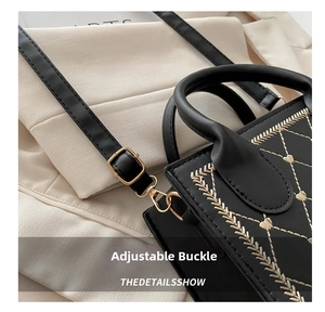 Macro view of adjustable buckle and golden leaf embroidery on black leather shoulder bag