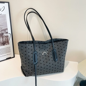Elegant grey striped tote bag with black bow print and metal buckle on display