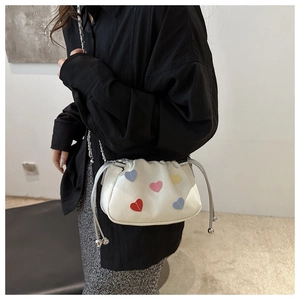 Détail du sac seau blanc à cordon avec motifs cœurs colorés et bandoulière chaîne