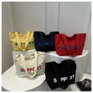 Five colored nylon tote bags with SUPPORT lettering in a minimalist studio setting