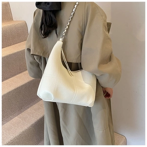 Gros plan d'un sac bandoulière croissant en cuir beige avec matelassage et chaîne argent