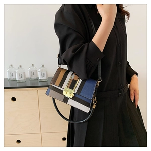 Detail of color-block crossbody bag with gold buckle and adjustable leather strap