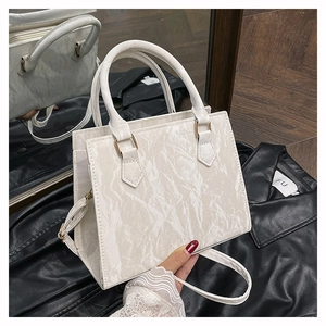 Close-up of white marble pattern PU leather handbag with elegant gold hardware and strap