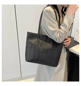 Close-up of black textured tote bag with vertical zebra pattern and brand logo